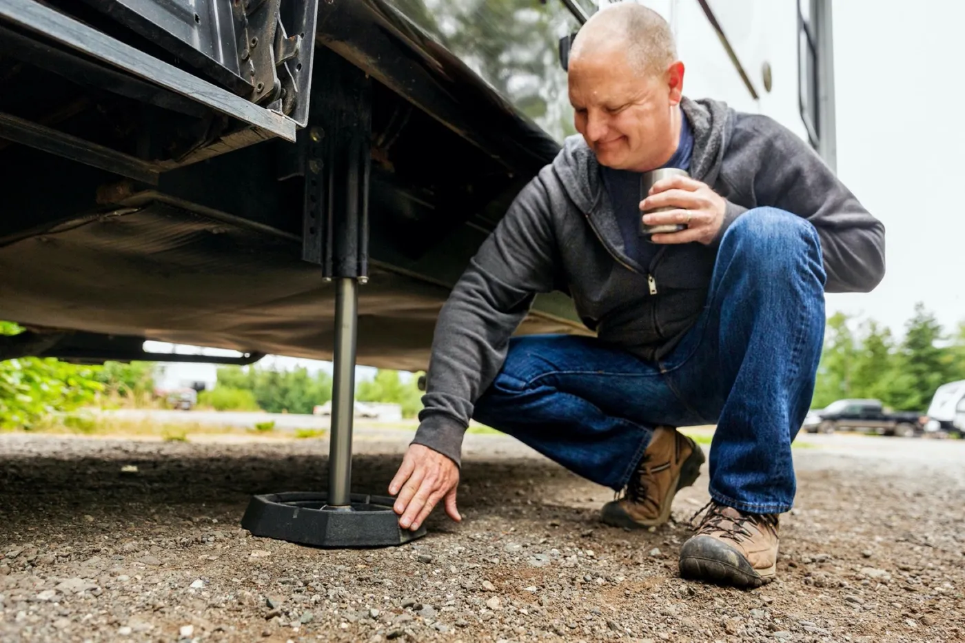 RVer crouching to look at a leveling jack fitted with a SnapPad