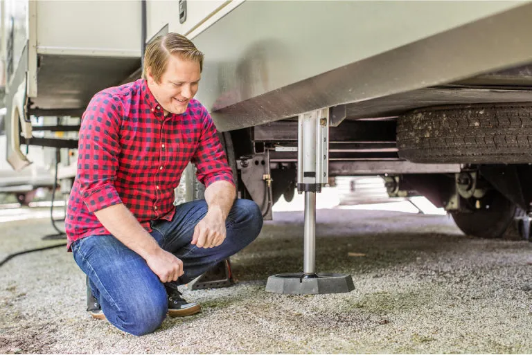 RVer kneeling beside a motorhome jack fitted with a SnapPad