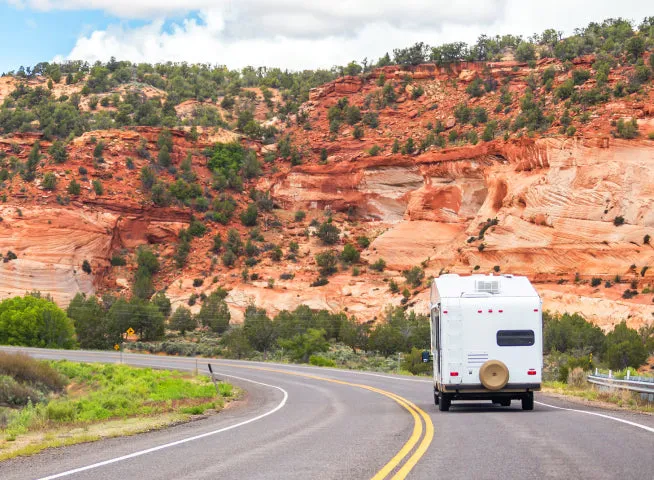 Class C motorhome on a highway through red rock canyon country